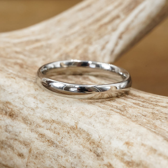 A Stainless Steel Wedding Band - Activity Band for women is elegantly displayed on a textured antler, set against a softly blurred brown background.