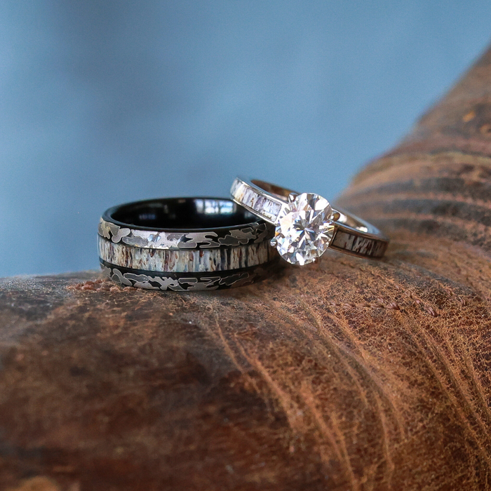 Two rings rest on a piece of brown leather: The Goliad, a sleek tungsten carbide ring with engraved details—perfect as a men’s wedding band—and a slimmer silver ring adorned with a round, sparkling diamond and rectangular inlaid stones.