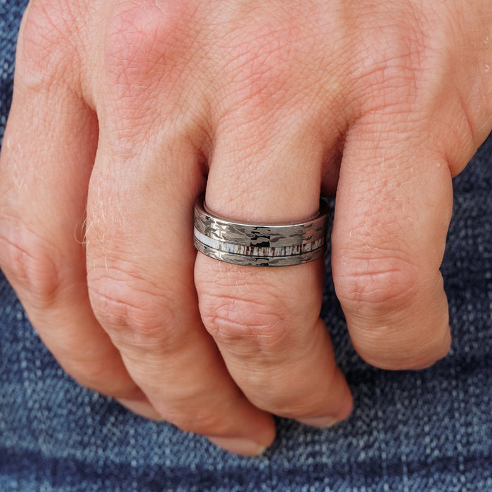 A close-up of a hand wearing The Kings Canyon, a textured silver antler ring, on the middle finger, with the person dressed in blue denim jeans.