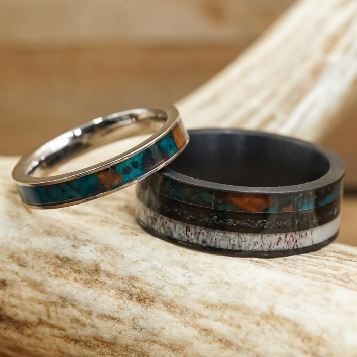 The Manchester & Patina Couples Set features two rings with striking blue-green and patina copper inlays, beautifully displayed on a piece of antler. One ring is a slender, silver-toned band crafted from tungsten carbide, while the other offers a wider, darker profile—both highlighting unique, earthy patterns. Designed as a couples ring set, these bands combine distinctive materials for an undeniably natural and eye-catching look.