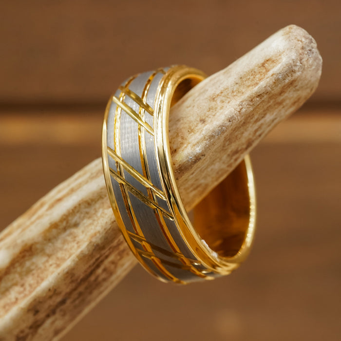 The Ogden features a gold striped band with geometric patterns resting on a light-colored antler, set against a blurred brown background.