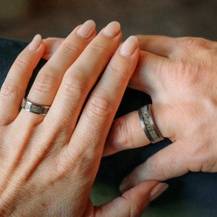 Two hands with neatly manicured nails are shown wearing The Smoky Mountain & Sedona Couples Set of silver rings on their ring fingers, positioned closely together in a gesture of connection or partnership. Each ring features a natural antler grain, adding a unique and organic touch reminiscent of the Sedona antler ring collection.