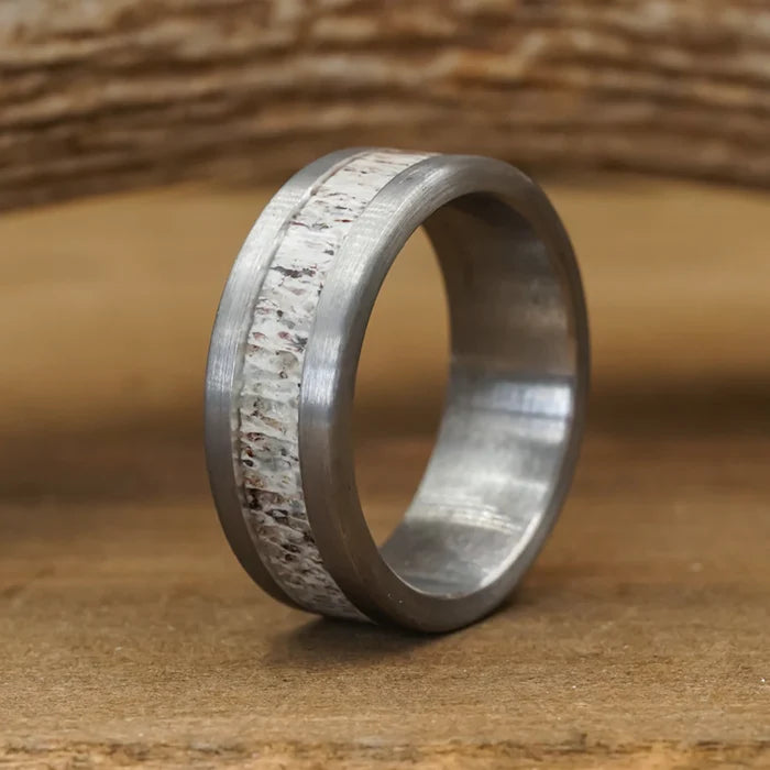 The Smoky Mountain & Sedona Couples Set features a silver ring with a matte finish and a central inlay showcasing a textured, speckled white and brown pattern reminiscent of natural antler grain, displayed on a wooden surface.