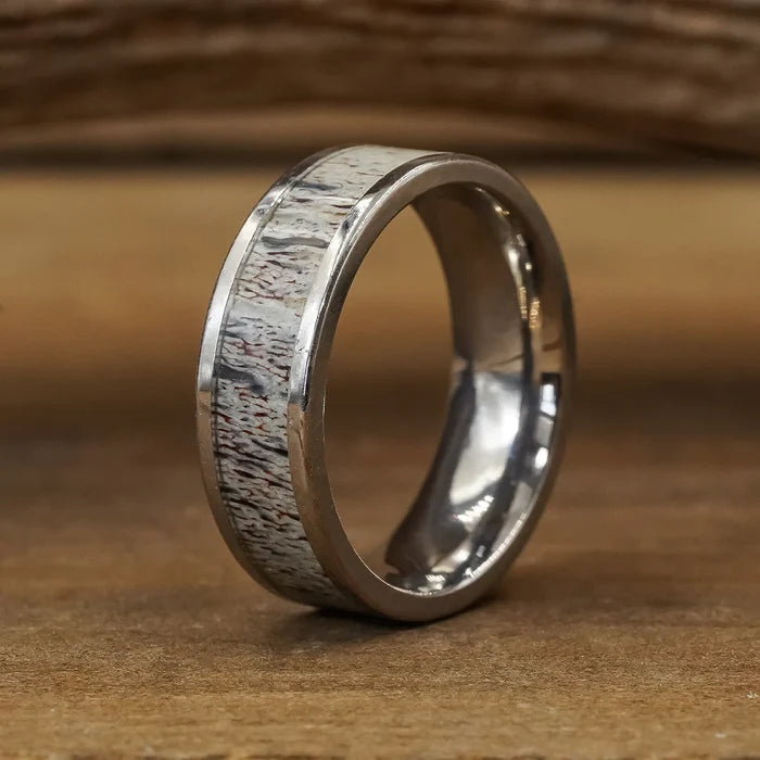 The Smoky Mountain & Sedona Couples Set features a silver ring with a textured, natural antler grain inlay, showcased upright on a wooden surface against a softly blurred wooden background.